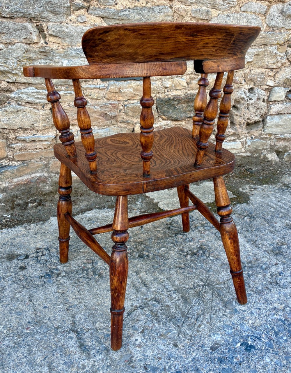 A Victorian elm captains armchair featuring a curved horseshoe rail, turned wooden spindles, and a deeply contoured saddle seat showing prominent wood grain. View VIII