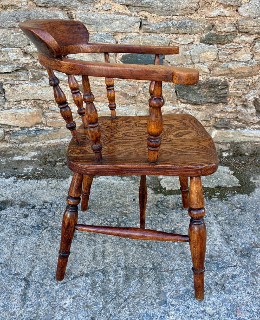 A Victorian elm captains armchair featuring a curved horseshoe rail, turned wooden spindles, and a deeply contoured saddle seat showing prominent wood grain. View IX