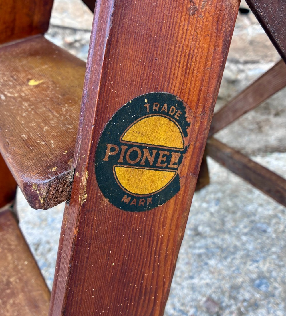 A vintage wooden folding step stool with three tread steps and metal side bracing finished in a warm reddish-brown stain. View V