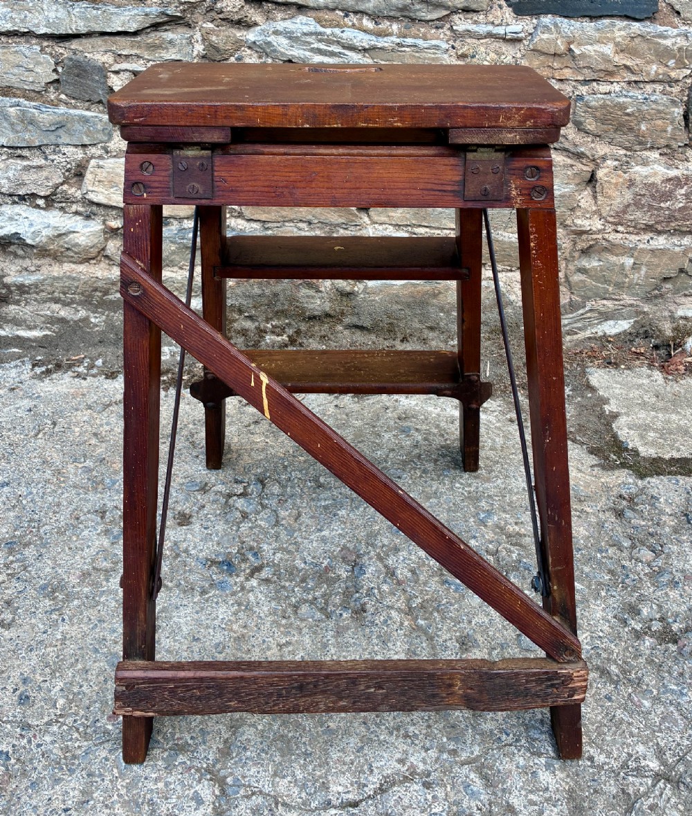 A vintage wooden folding step stool with three tread steps and metal side bracing finished in a warm reddish-brown stain. View VII
