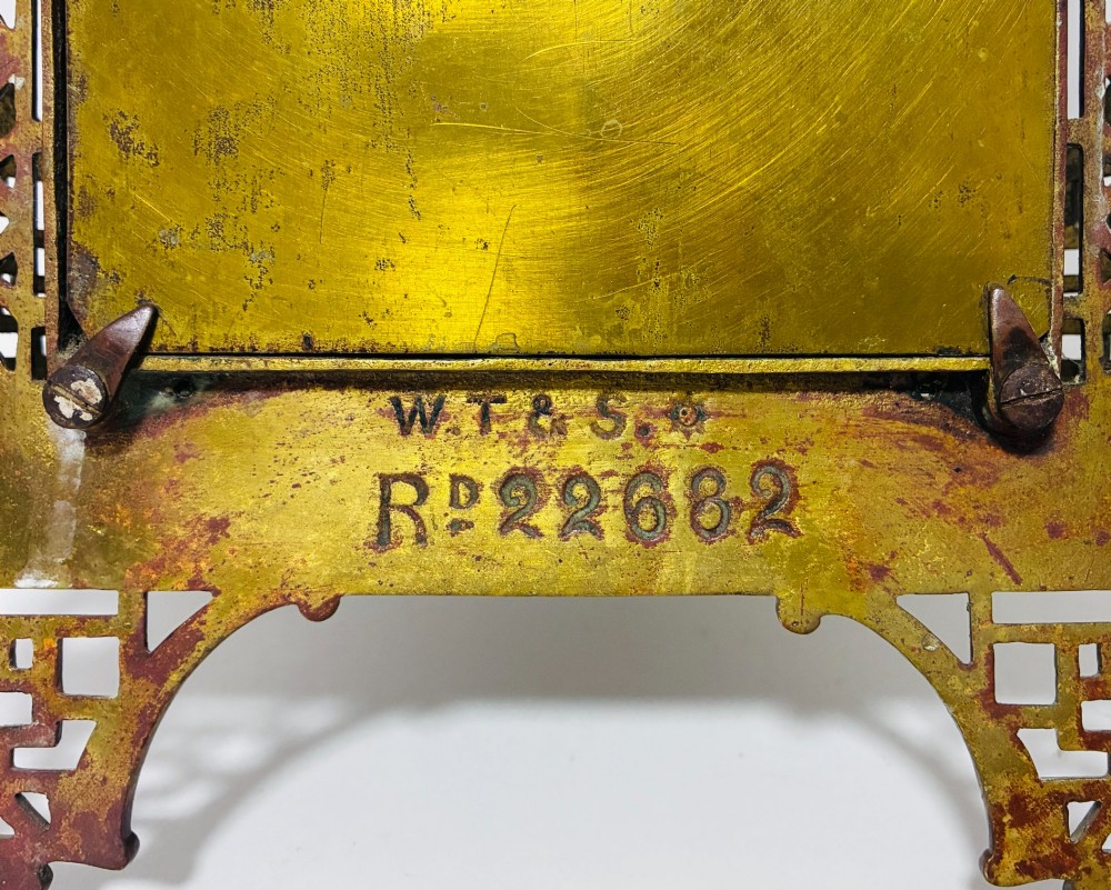 An ornate cast brass wall mirror featuring a central bevelled glass plate, openwork lattice frame, top mask cresting, and an integrated lower tray. View VIII