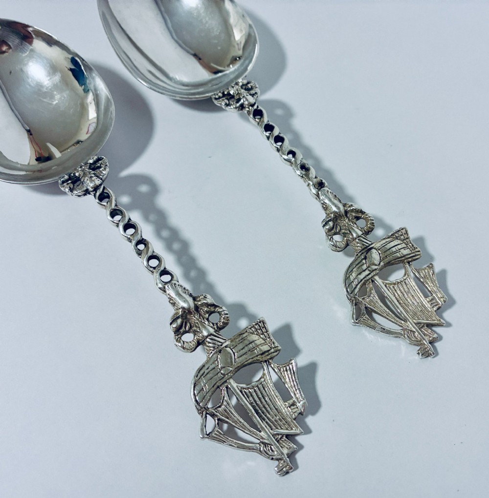 A pair of antique silver spoons featuring oval bowls, decorative spiral stems, and detailed sailing ship finials displayed against a plain background. View II