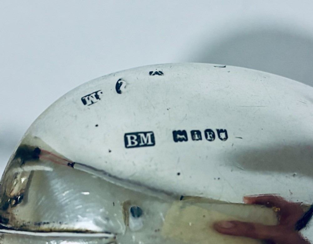 A pair of antique silver spoons featuring oval bowls, decorative spiral stems, and detailed sailing ship finials displayed against a plain background. View IX
