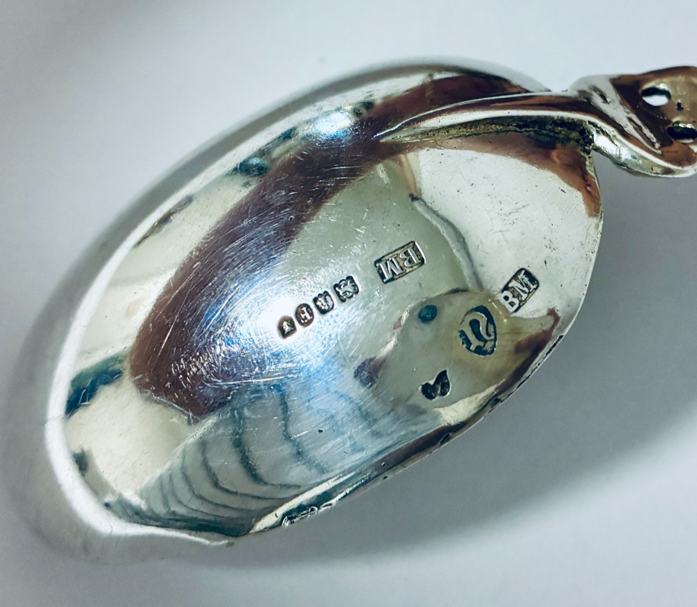 A pair of antique silver spoons featuring oval bowls, decorative spiral stems, and detailed sailing ship finials displayed against a plain background. View X