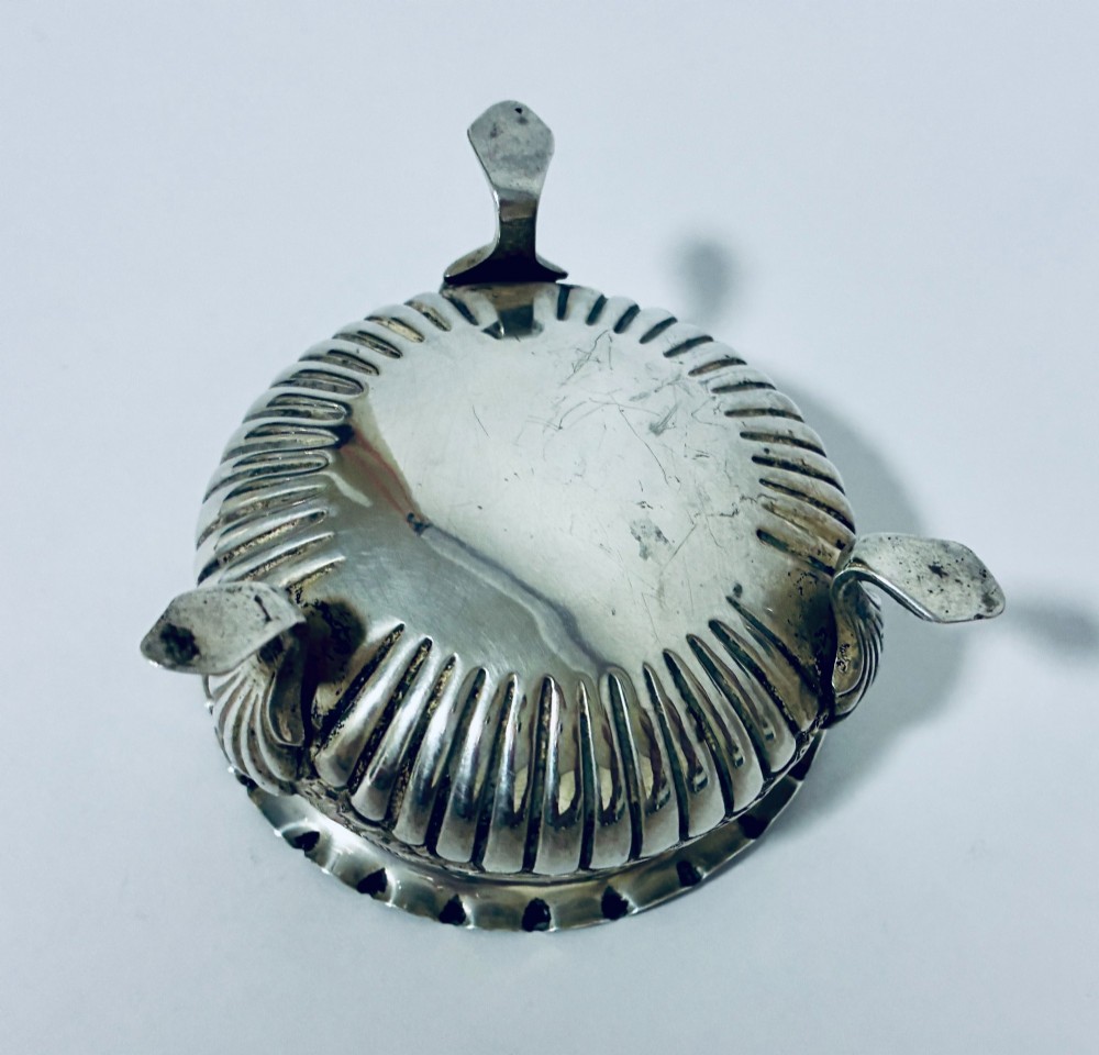 A small Victorian sterling silver salt dish with a crimped rim, chased floral decoration, fluted lower body, and three tripod legs. View VI