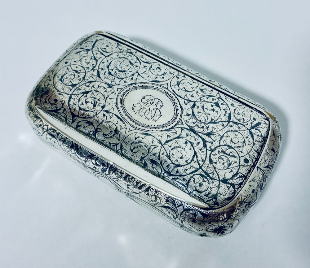 A small, rectangular silver snuff box with rounded corners featuring intricate hand-engraved scrollwork patterns and a central oval cartouche. View II