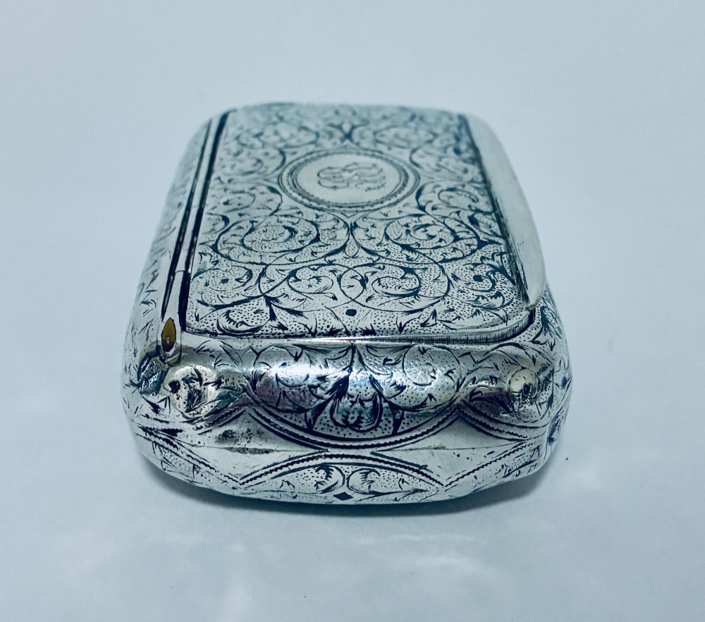 A small, rectangular silver snuff box with rounded corners featuring intricate hand-engraved scrollwork patterns and a central oval cartouche. View IX