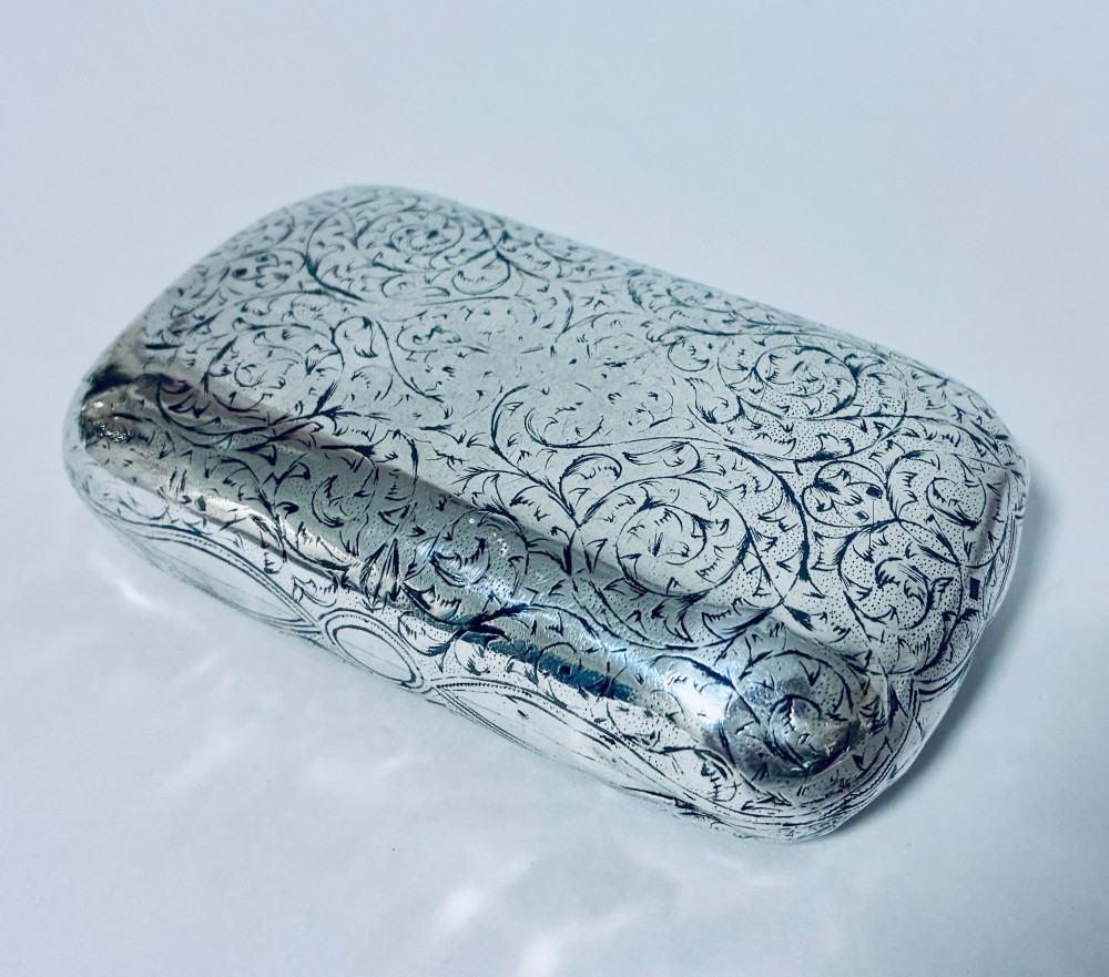 A small, rectangular silver snuff box with rounded corners featuring intricate hand-engraved scrollwork patterns and a central oval cartouche. View XI