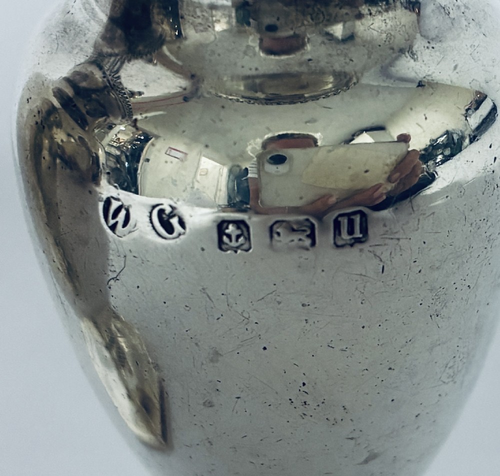 A pair of hallmarked sterling silver baluster pepper pots featuring pierced domed lids with finials and octagonal pedestal bases. View II