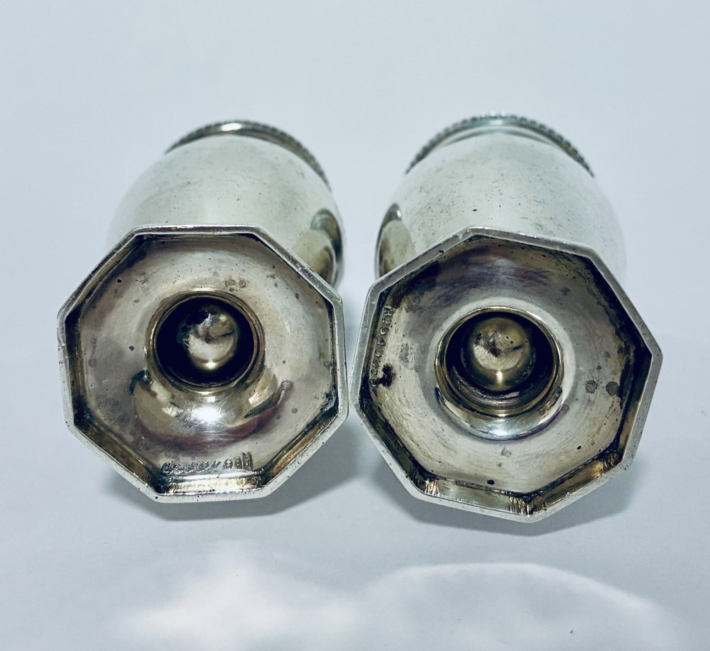 A pair of hallmarked sterling silver baluster pepper pots featuring pierced domed lids with finials and octagonal pedestal bases. View VII