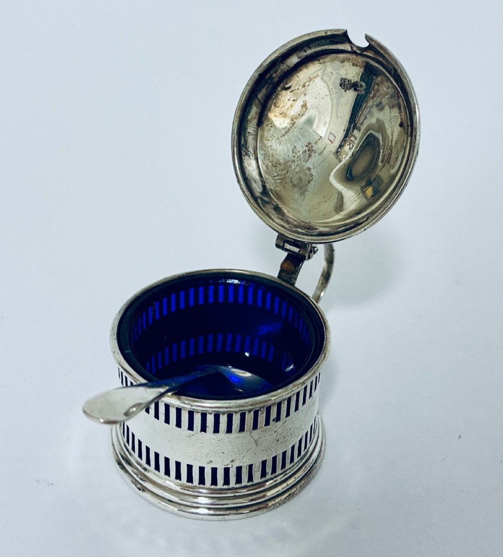 An antique three-piece silver cruet set featuring pierced vertical slot details, a mustard pot with lid and spoon, and two matching pepper casters. View XI