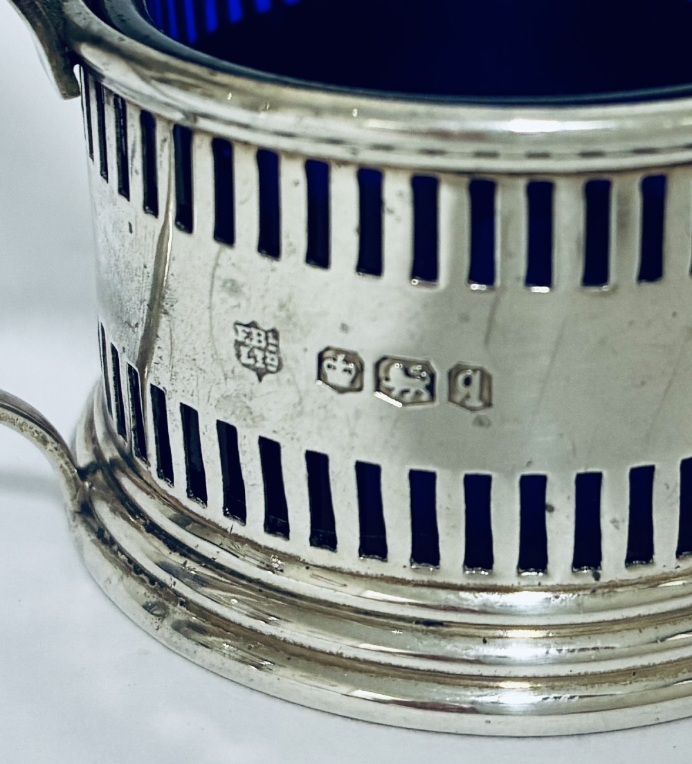 An antique three-piece silver cruet set featuring pierced vertical slot details, a mustard pot with lid and spoon, and two matching pepper casters. View XIII
