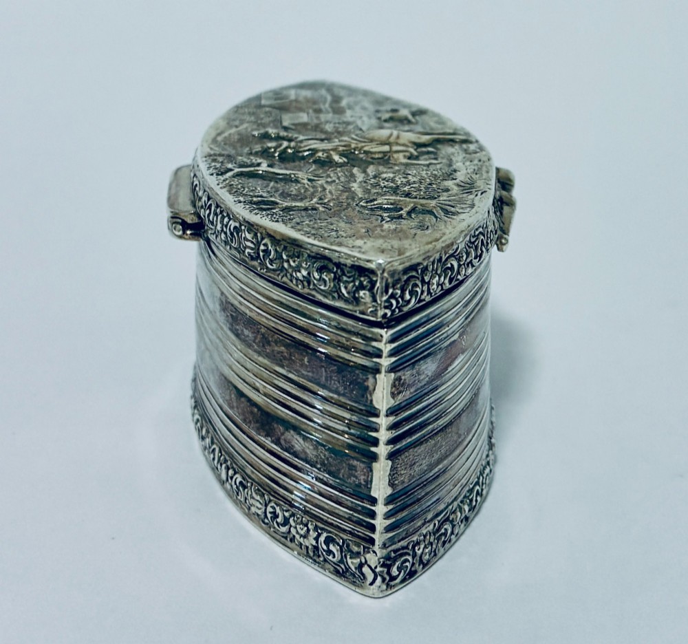 An oval silver snuff box featuring a relief equestrian scene on the hinged lid and reeded side walls with carved scroll borders. View VII