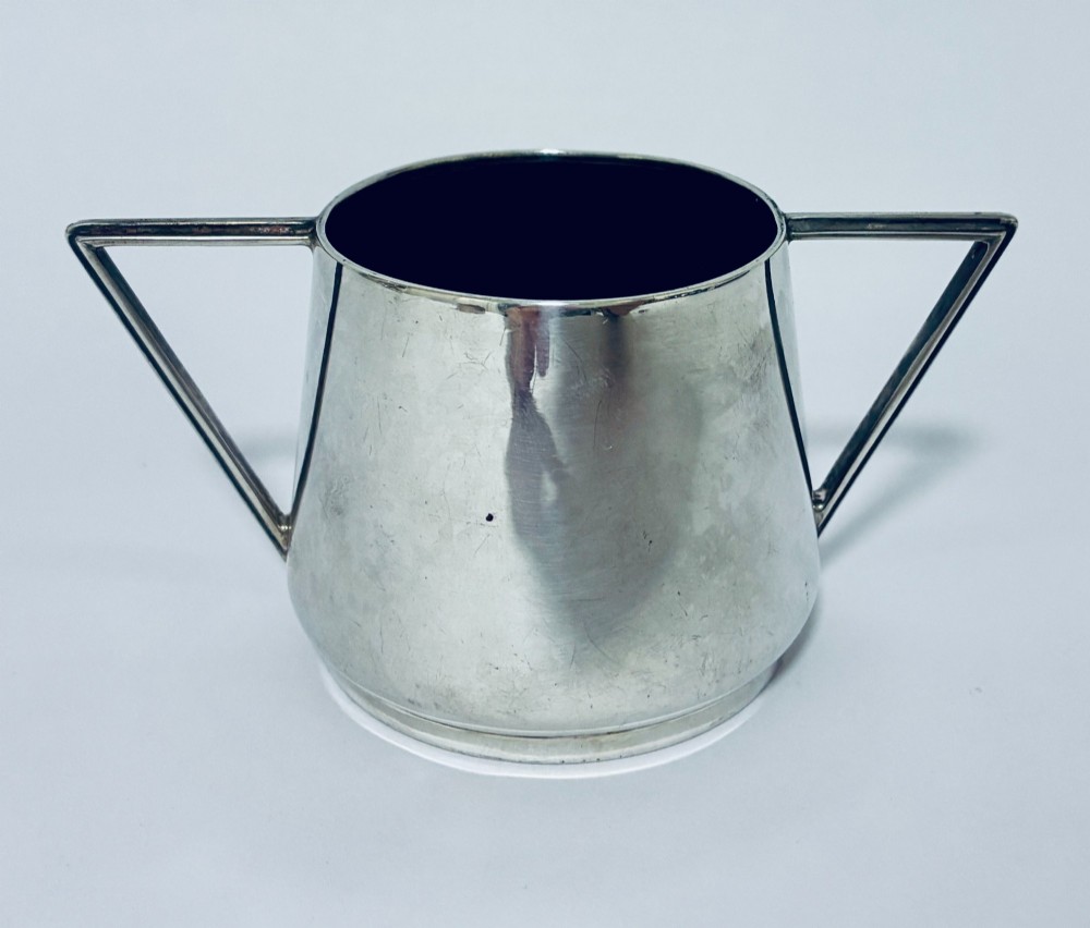 A polished sterling silver Art Deco sugar bowl with sharp triangular side handles and visible hallmarks stamped on the exterior wall. View IV