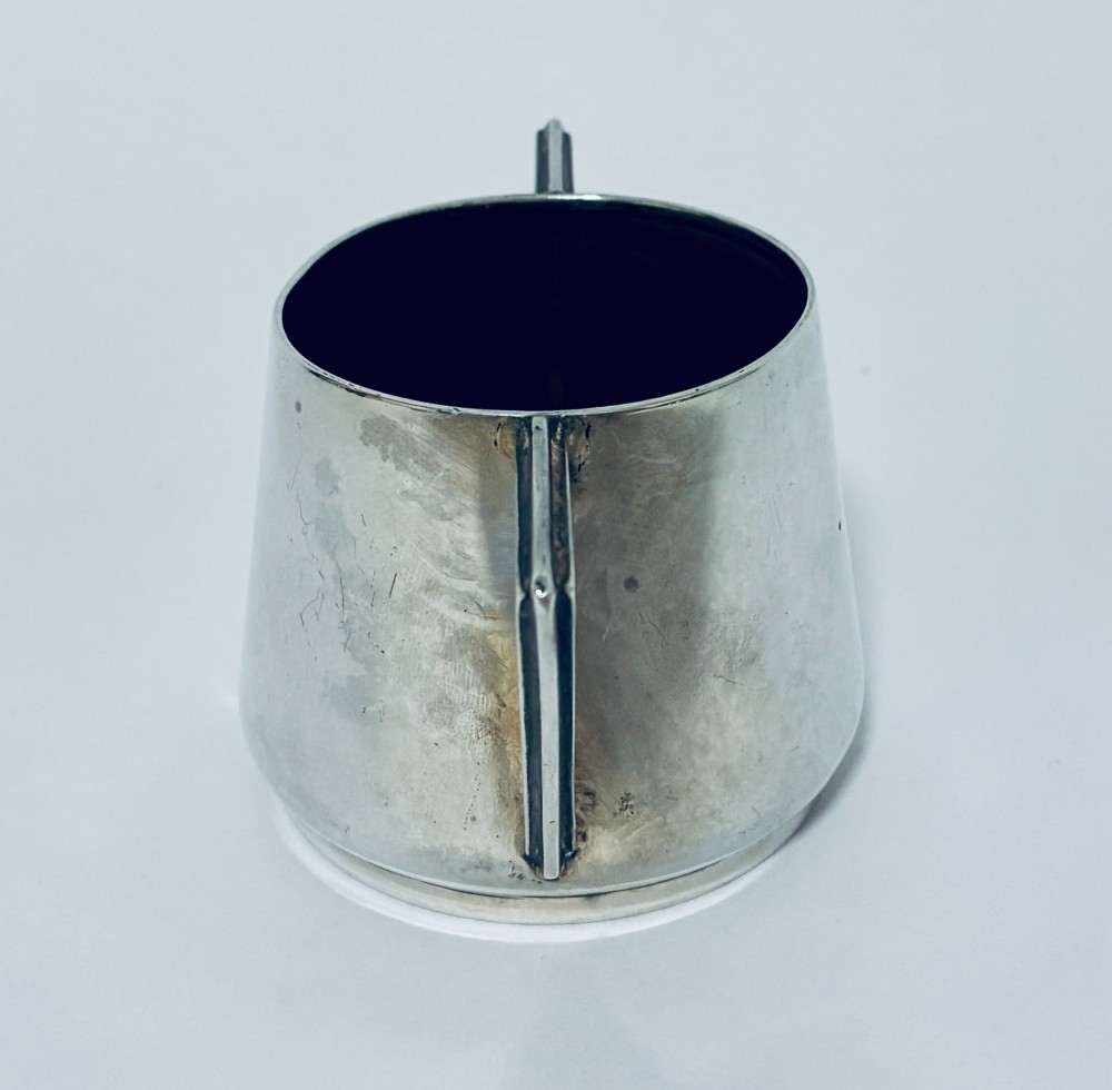 A polished sterling silver Art Deco sugar bowl with sharp triangular side handles and visible hallmarks stamped on the exterior wall. View V
