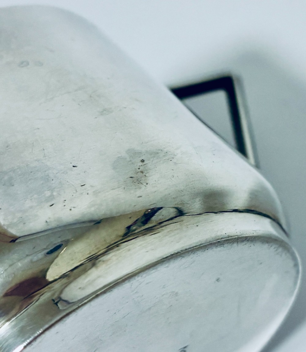 A polished sterling silver Art Deco sugar bowl with sharp triangular side handles and visible hallmarks stamped on the exterior wall. View VII