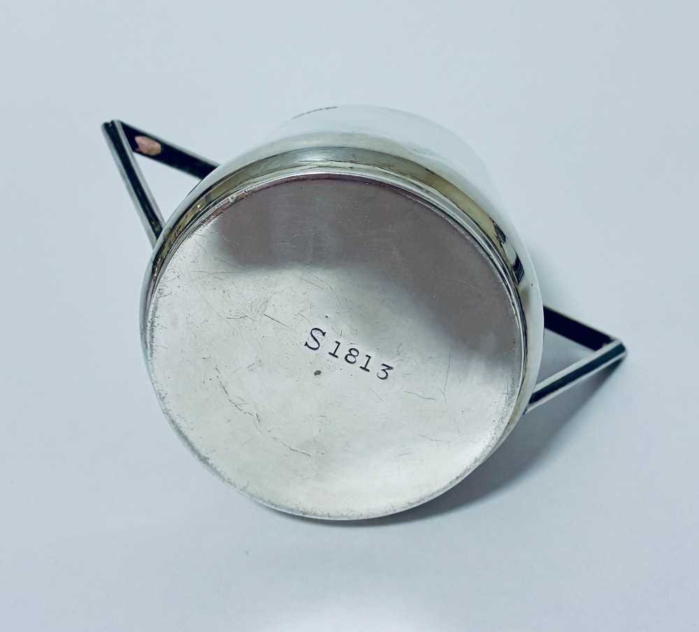 A polished sterling silver Art Deco sugar bowl with sharp triangular side handles and visible hallmarks stamped on the exterior wall. View VIII
