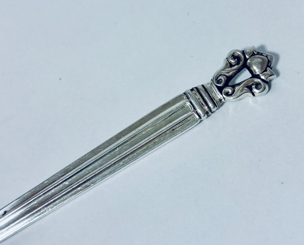A sterling silver ladle featuring a deep bowl, a ribbed tapered handle, and a decorative scroll motif at the terminal. View II