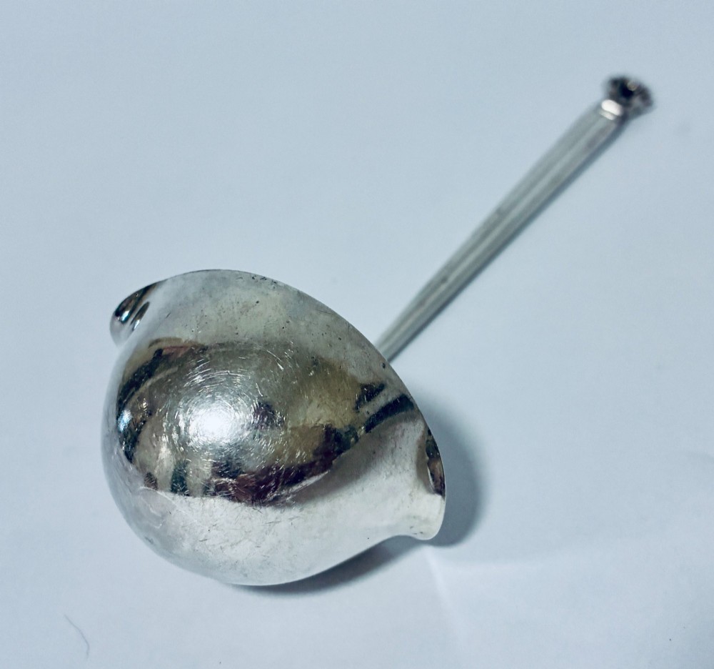 A sterling silver ladle featuring a deep bowl, a ribbed tapered handle, and a decorative scroll motif at the terminal. View IV