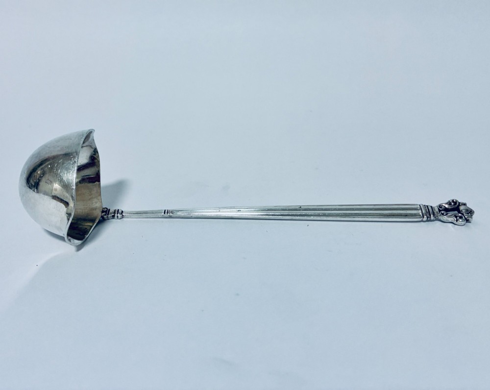 A sterling silver ladle featuring a deep bowl, a ribbed tapered handle, and a decorative scroll motif at the terminal. View V