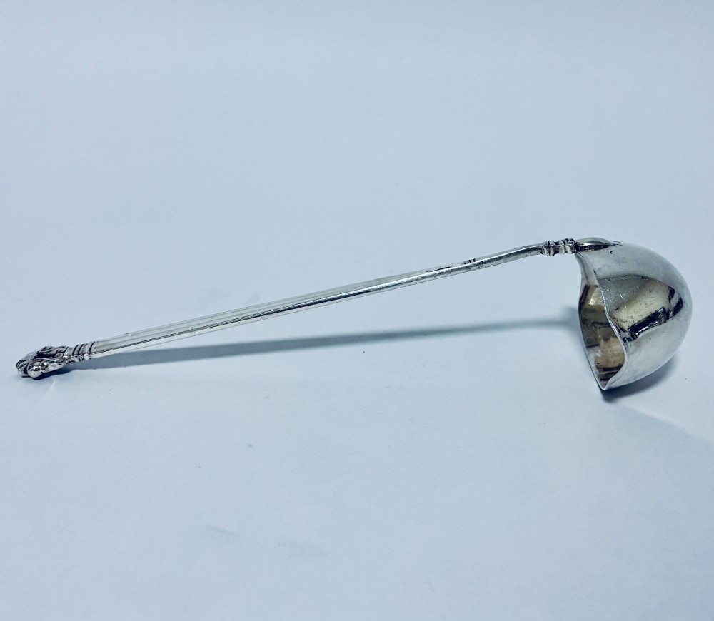 A sterling silver ladle featuring a deep bowl, a ribbed tapered handle, and a decorative scroll motif at the terminal. View VIII