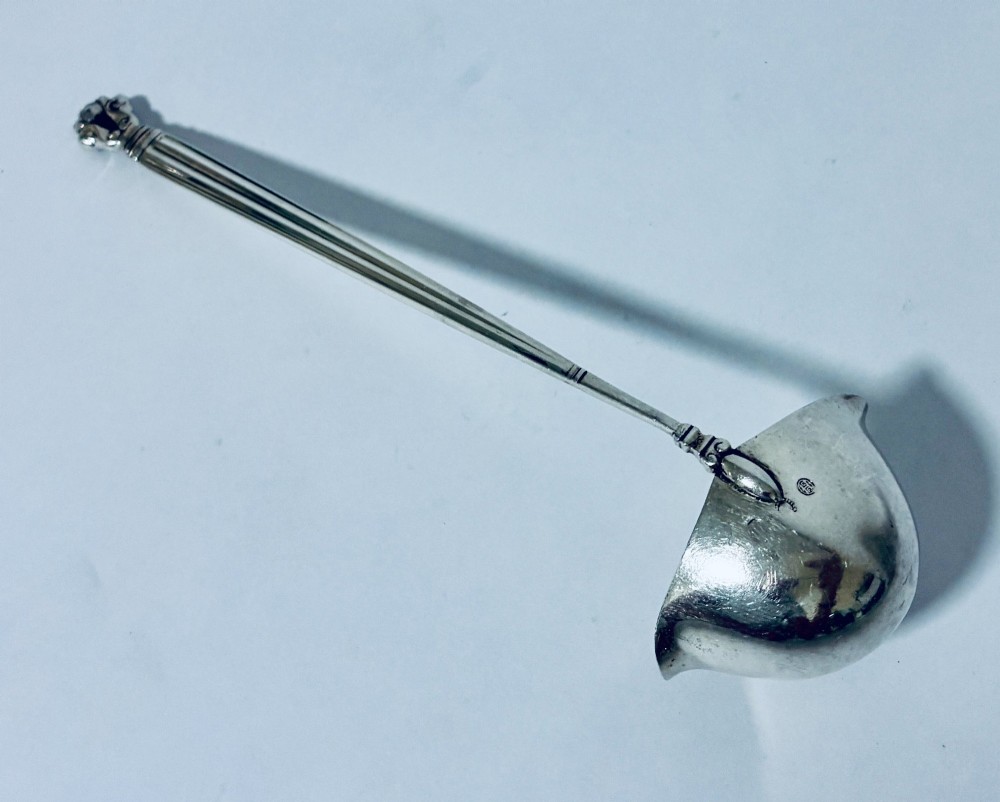 A sterling silver ladle featuring a deep bowl, a ribbed tapered handle, and a decorative scroll motif at the terminal. View IX