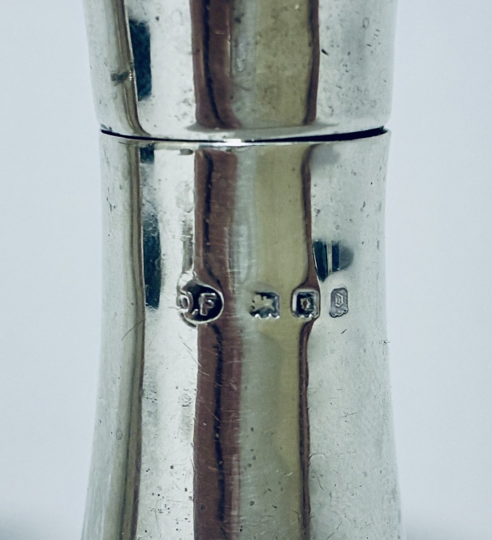 A pair of hallmarked sterling silver pepper pots featuring flared bodies, pierced tops, and turned finials. View II