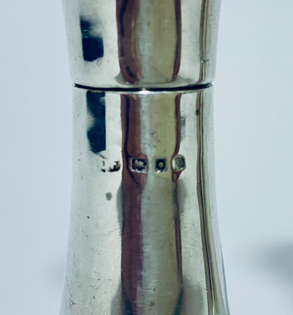 A pair of hallmarked sterling silver pepper pots featuring flared bodies, pierced tops, and turned finials. View III