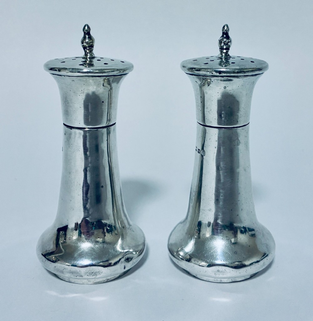 A pair of hallmarked sterling silver pepper pots featuring flared bodies, pierced tops, and turned finials. View IV