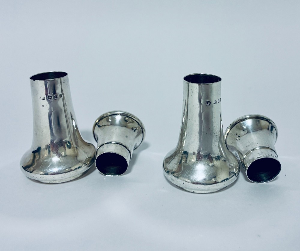 A pair of hallmarked sterling silver pepper pots featuring flared bodies, pierced tops, and turned finials. View VII