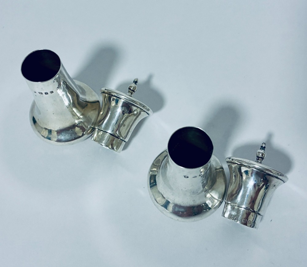 A pair of hallmarked sterling silver pepper pots featuring flared bodies, pierced tops, and turned finials. View VIII
