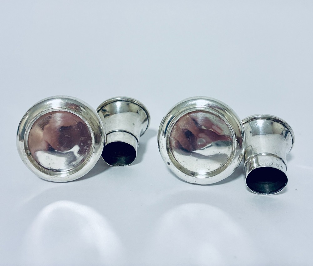 A pair of hallmarked sterling silver pepper pots featuring flared bodies, pierced tops, and turned finials. View IX