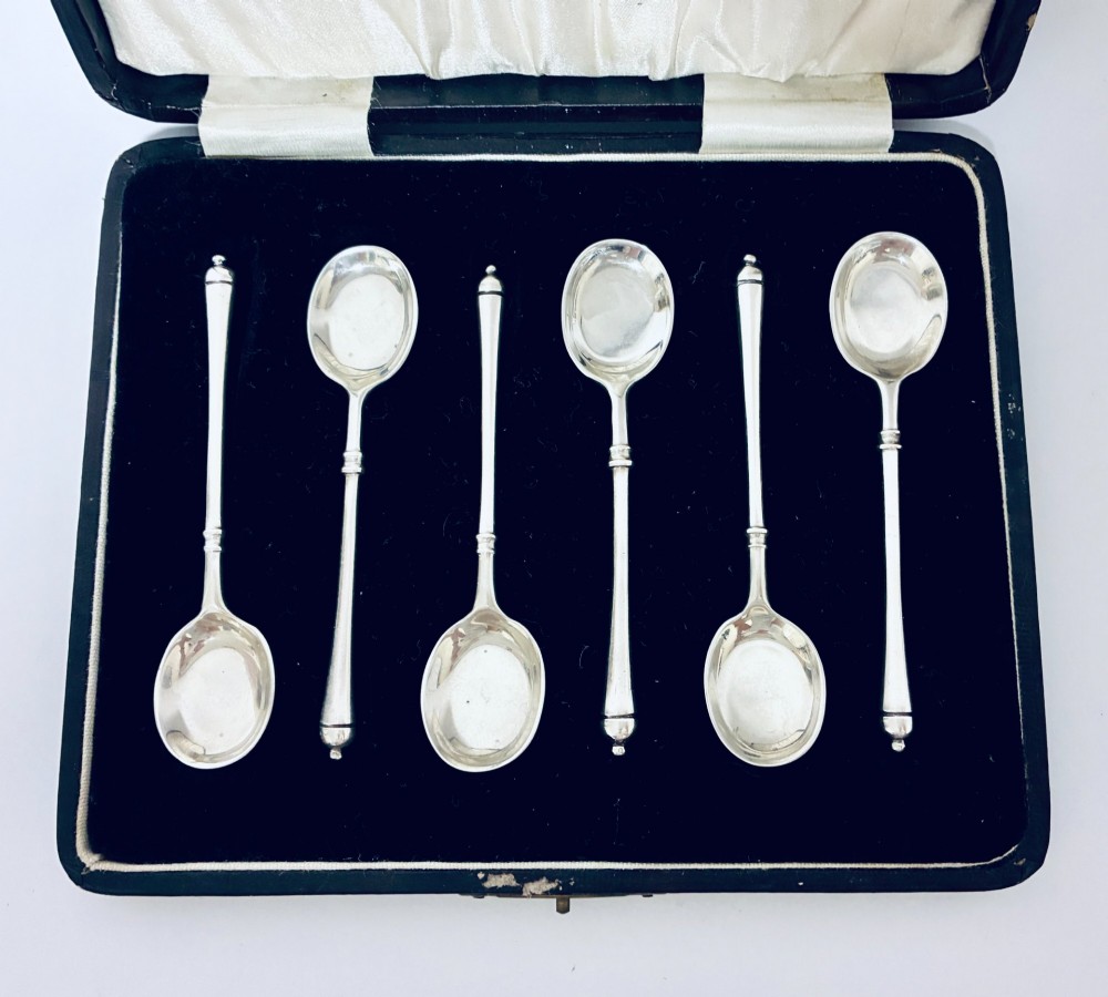 A set of six silver coffee spoons with turned handles stored inside a black fitted presentation case lined with velvet and cream satin. View II