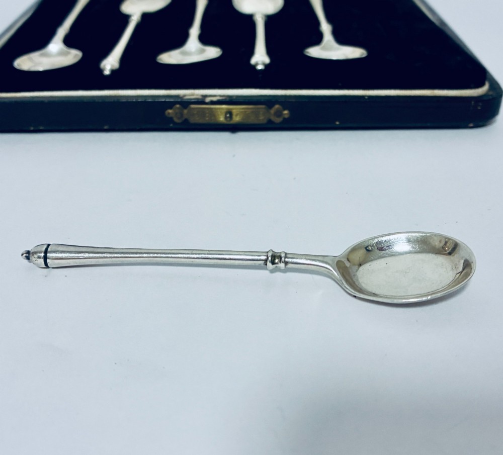 A set of six silver coffee spoons with turned handles stored inside a black fitted presentation case lined with velvet and cream satin. View IV