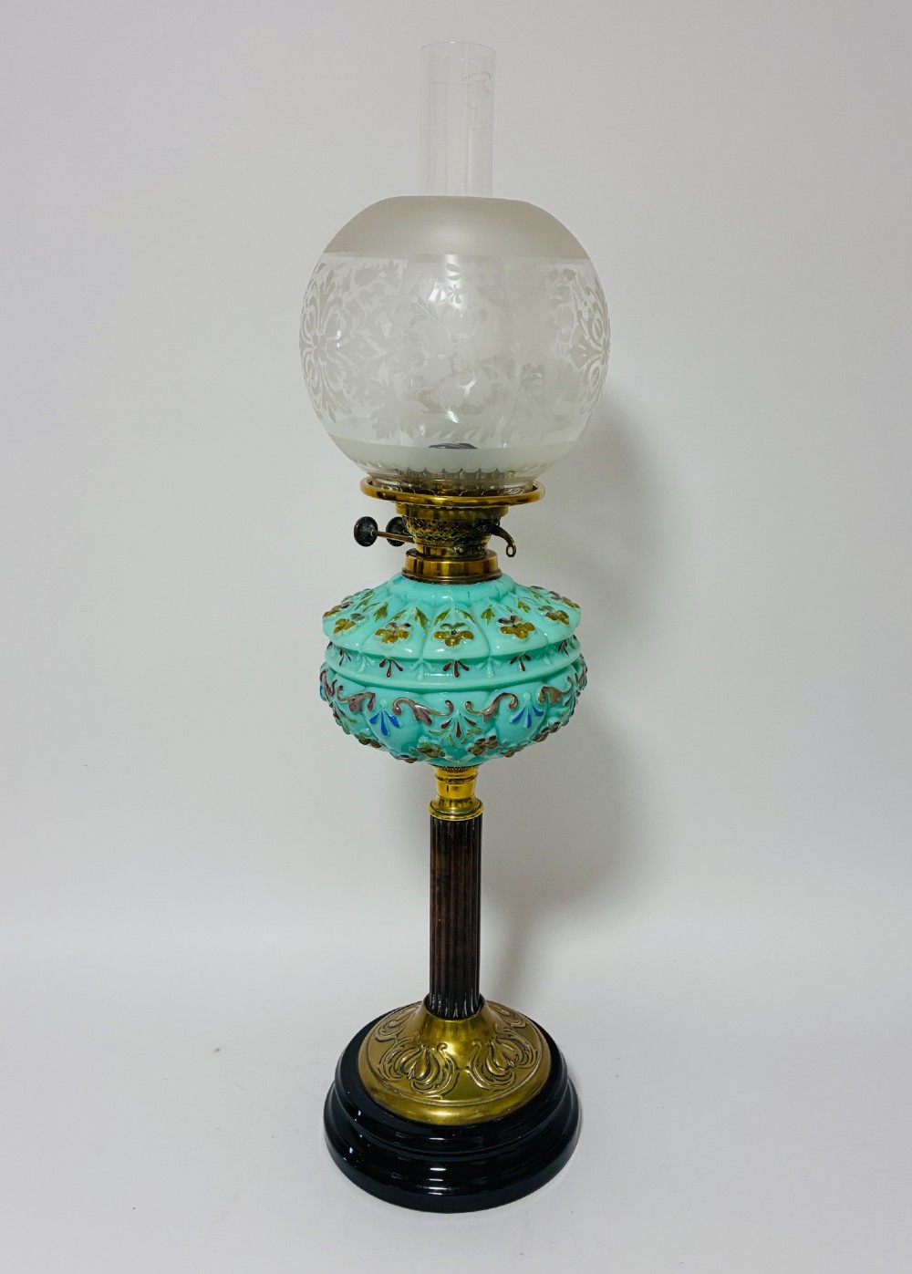 A Victorian oil lamp featuring an etched frosted glass shade, a turquoise enamelled font, and a brass column on a dark stepped base.