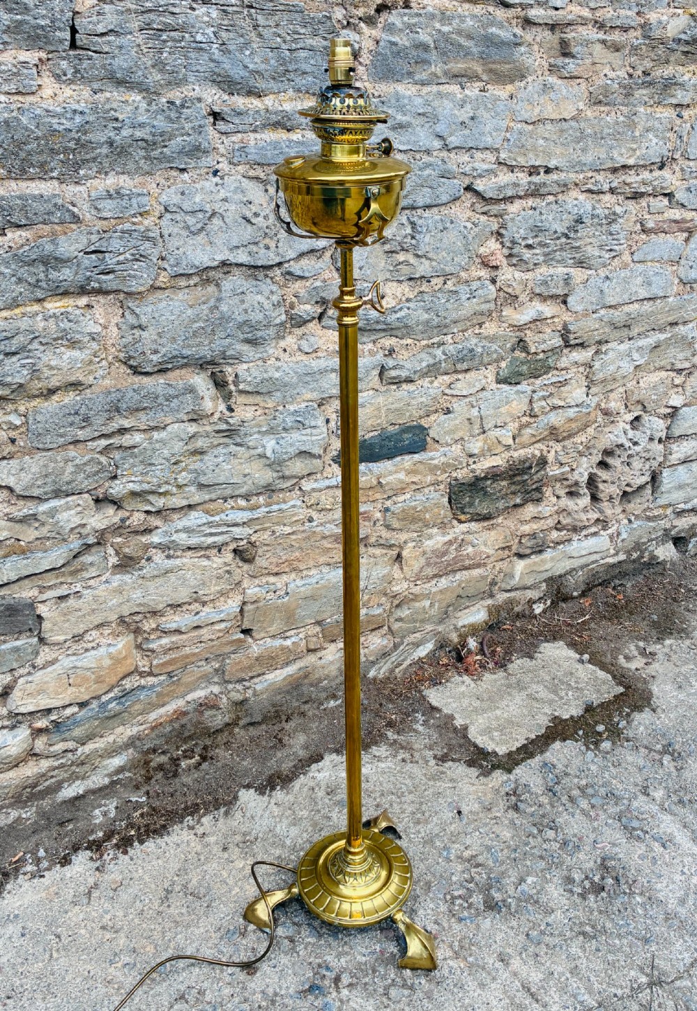 A Victorian brass telescopic floor lamp featuring a ornate tripod base, adjustable vertical stem, and converted oil font fitted with an electrical lamp holder. View VIII