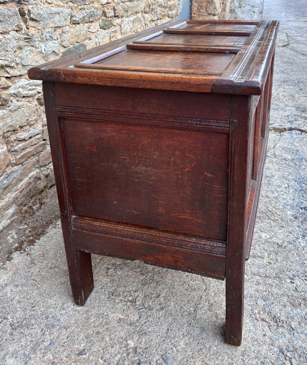 A dark oak 17th century coffer featuring a three-panel carved front with geometric scrollwork and a hinged rectangular lid. View IV