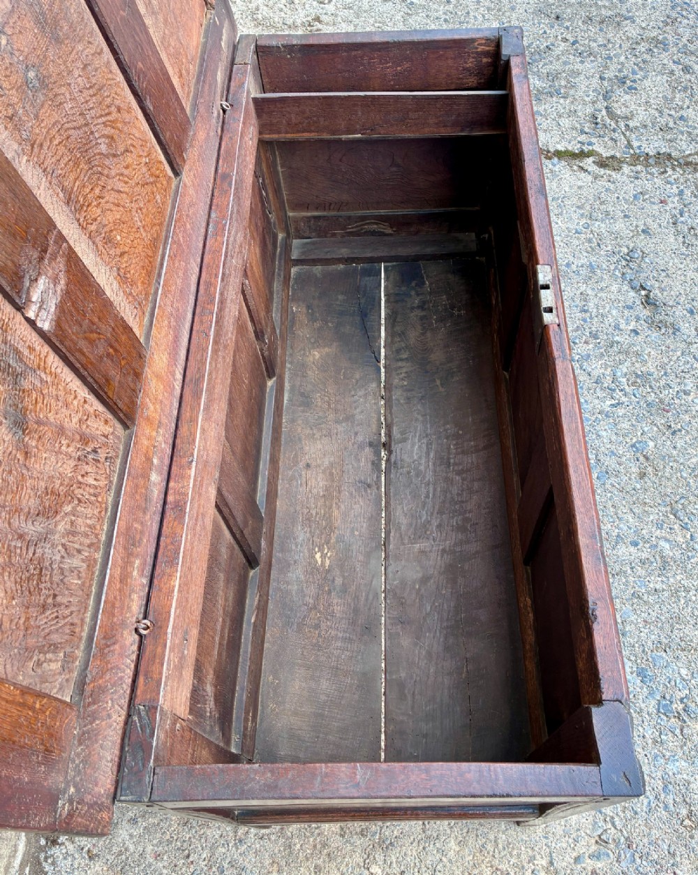 A dark oak 17th century coffer featuring a three-panel carved front with geometric scrollwork and a hinged rectangular lid. View VIII