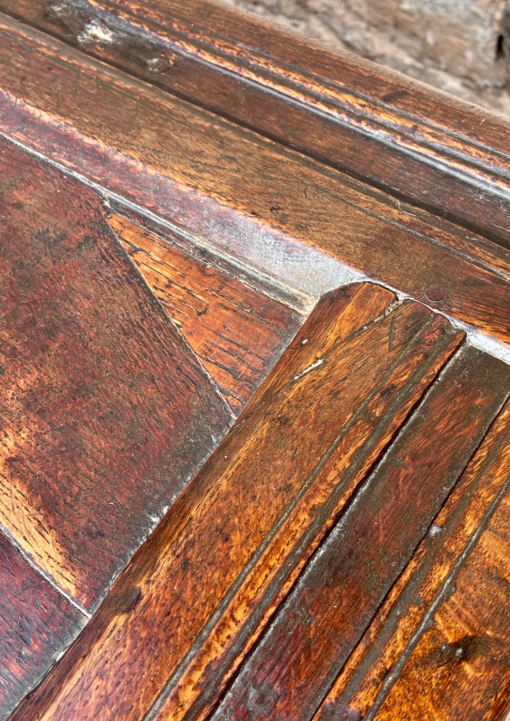 A dark oak 17th century coffer featuring a three-panel carved front with geometric scrollwork and a hinged rectangular lid. View XII