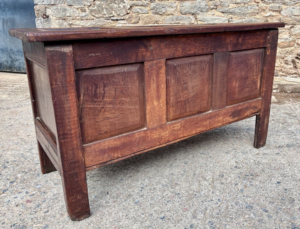 A dark oak 17th century coffer featuring a three-panel carved front with geometric scrollwork and a hinged rectangular lid. View XIV