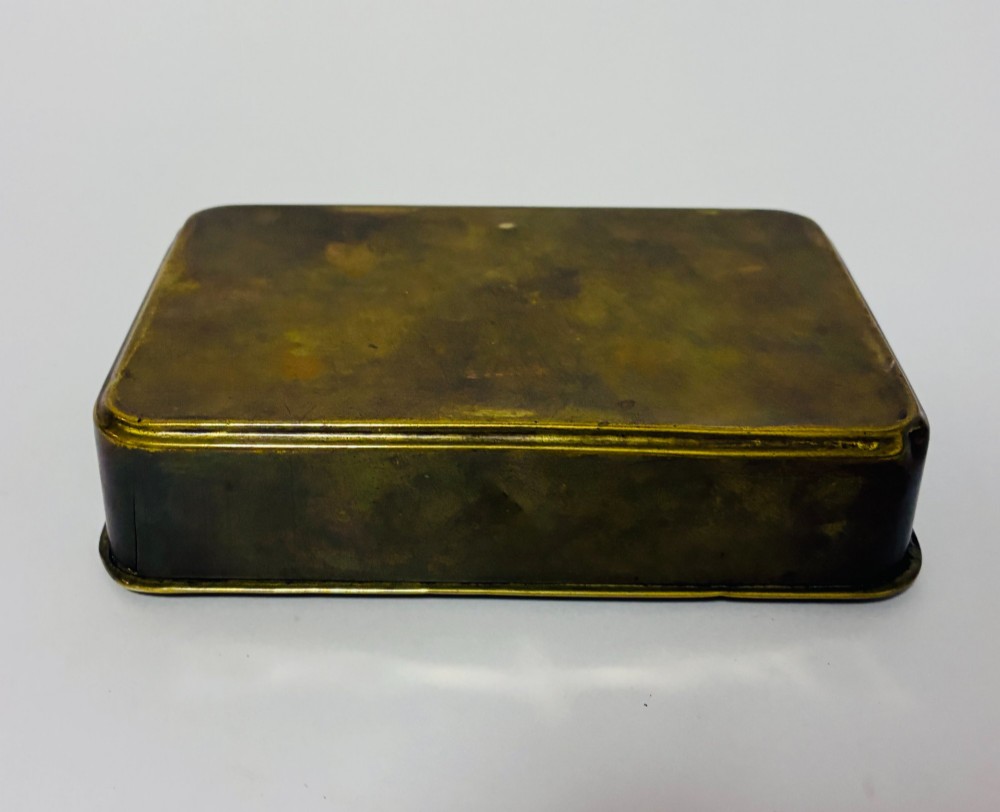 An embossed rectangular brass Princess Mary Christmas tin alongside its original cream greeting card printed with a red royal monogram. View IX