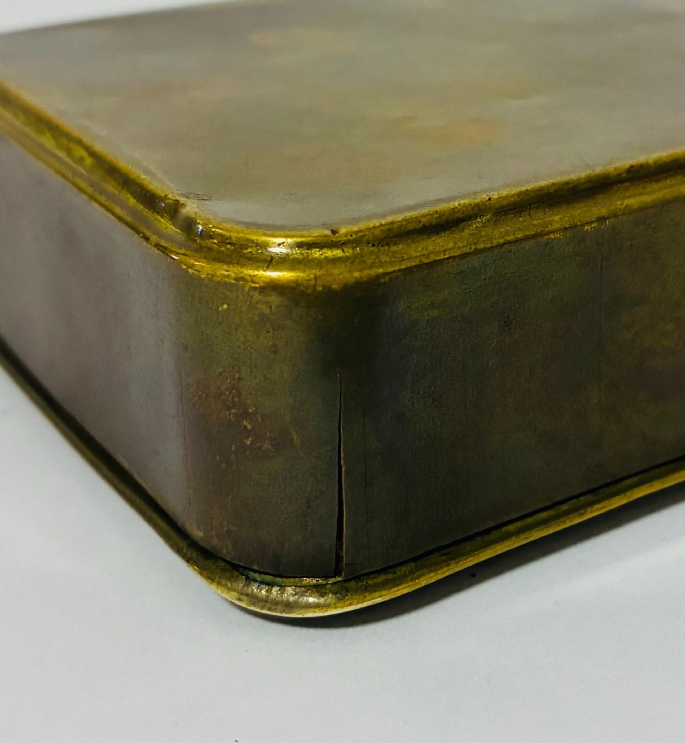 An embossed rectangular brass Princess Mary Christmas tin alongside its original cream greeting card printed with a red royal monogram. View XI