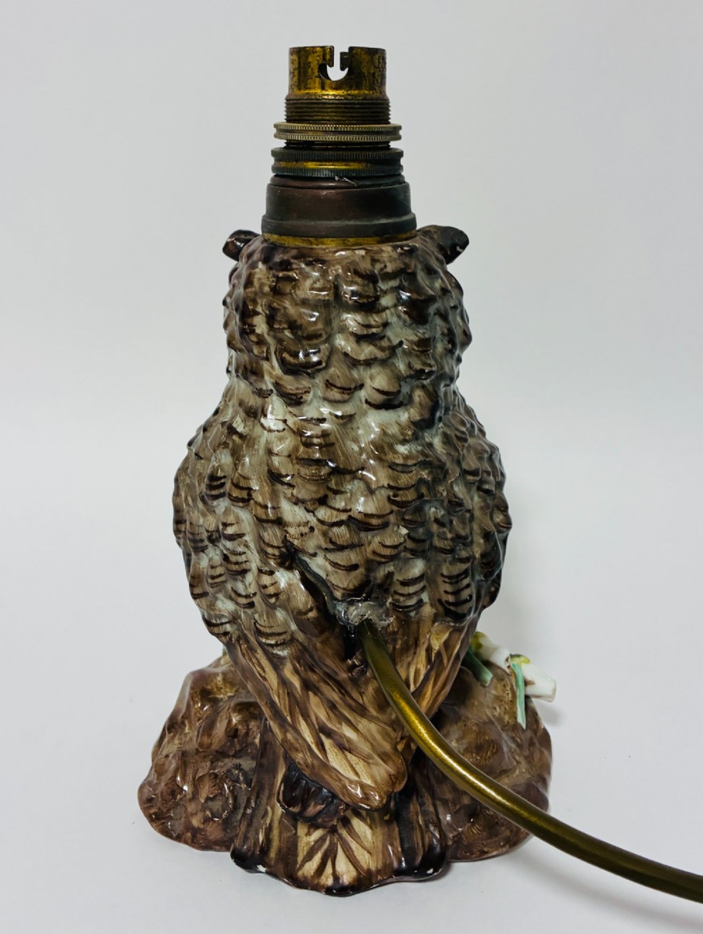 A glazed ceramic table lamp base crafted in the shape of an owl with yellow glass eyes, standing on a foliage-adorned base beneath a brass bulb holder. View III