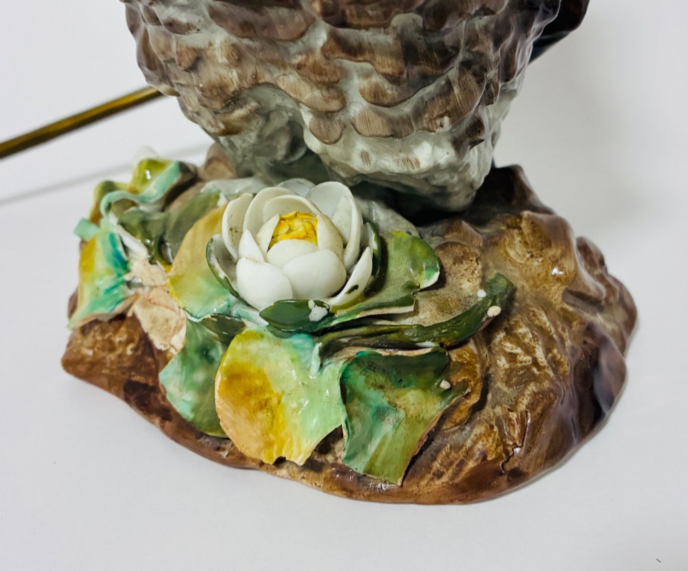 A glazed ceramic table lamp base crafted in the shape of an owl with yellow glass eyes, standing on a foliage-adorned base beneath a brass bulb holder. View VI