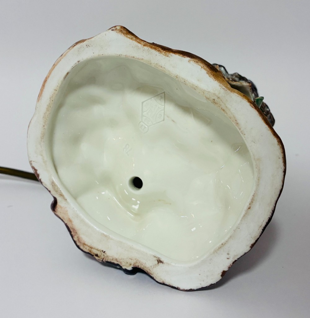 A glazed ceramic table lamp base crafted in the shape of an owl with yellow glass eyes, standing on a foliage-adorned base beneath a brass bulb holder. View IX