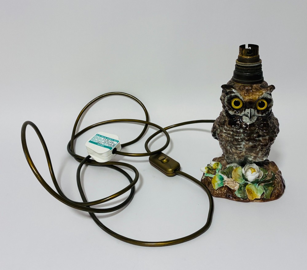 A glazed ceramic table lamp base crafted in the shape of an owl with yellow glass eyes, standing on a foliage-adorned base beneath a brass bulb holder. View XI
