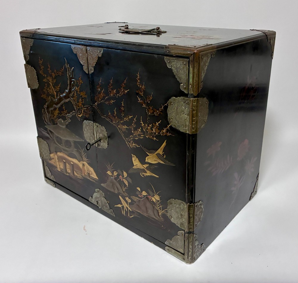 An antique Japanese black lacquer table cabinet decorated with gold bird and landscape scenes, fitted with metal corner brackets and a top handle. View IX
