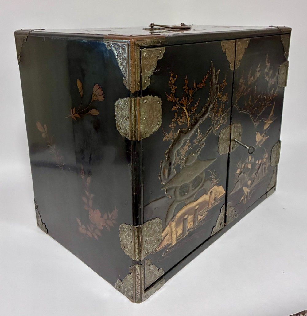An antique Japanese black lacquer table cabinet decorated with gold bird and landscape scenes, fitted with metal corner brackets and a top handle. View XV