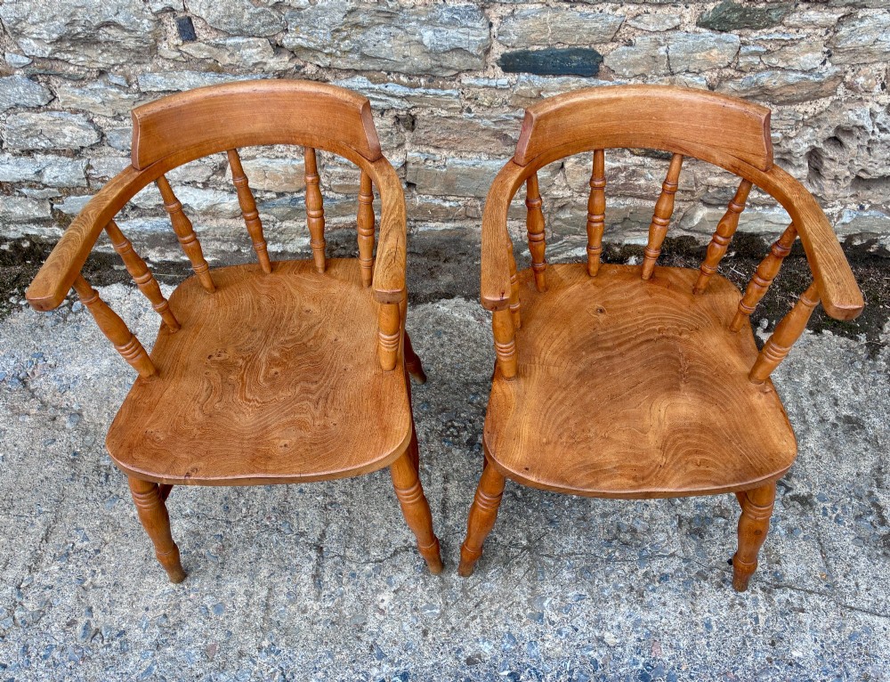 A pair of antique wooden captains chairs with contoured elm seats, turned spindles, rounded armrests, and turned legs. View II