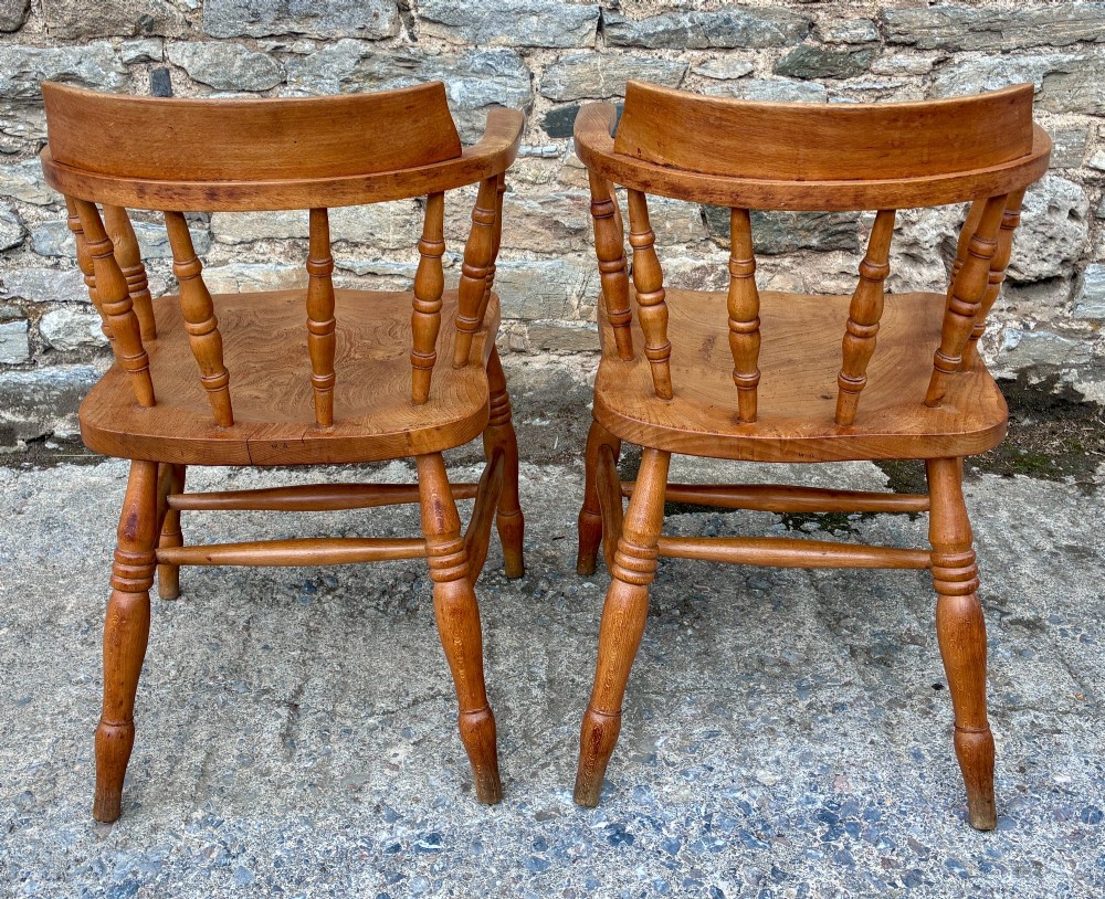 A pair of antique wooden captains chairs with contoured elm seats, turned spindles, rounded armrests, and turned legs. View IV